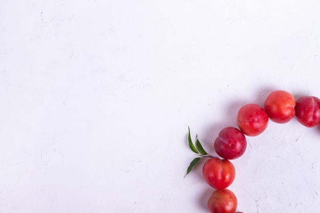 Ripe red plums with green leaves from a tree