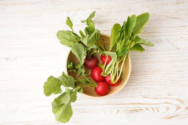 Photo ripe red radish in a bowl on a wooden background top view fresh red radish