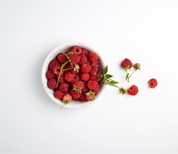 Ripe red raspberries in a wooden white plate 