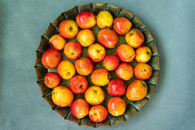 Ripe red small Ranetka apples on a metal plate on a gray or blue background