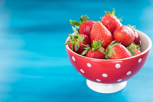 Ripe red strawberries on blue wooden table