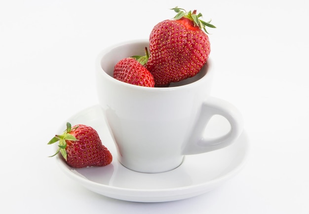 Ripe red strawberries in a cup on a white background