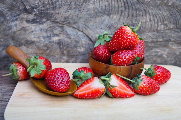 Ripe red strawberries in wood bowl on wooden table background