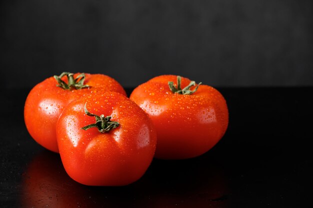 Ripe red tomatoes on a black space. Farm vegetables for a healthy diet.