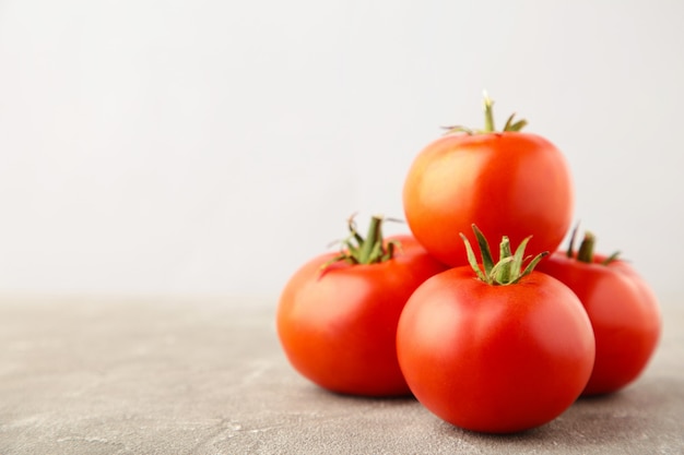 Ripe red tomatoes on a grey background.