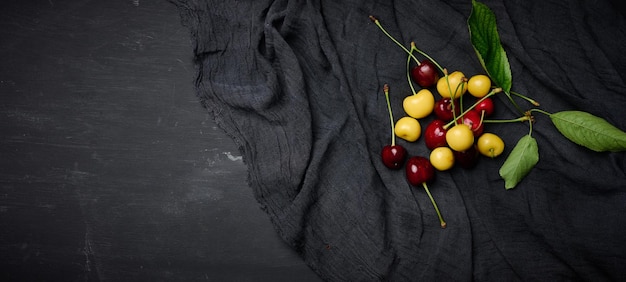 Ripe red and yellow cherries on a black background summer berry