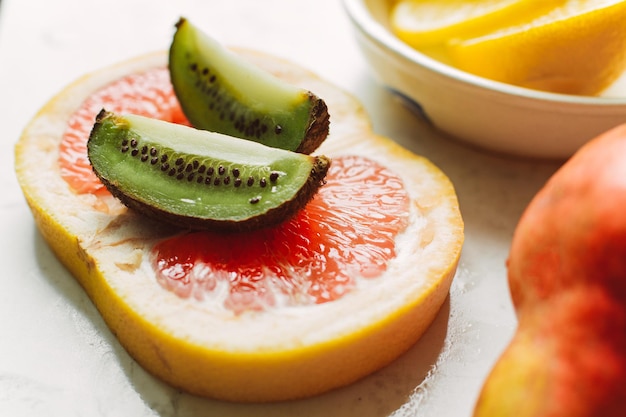 Ripe sliced fruits on a stone background grapefruit kiwi lemon pear