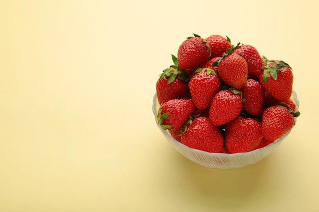 Ripe strawberries in bowl on beige background Space for text