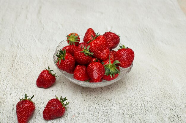 Ripe strawberries in a crystal bowl that stands on a white table