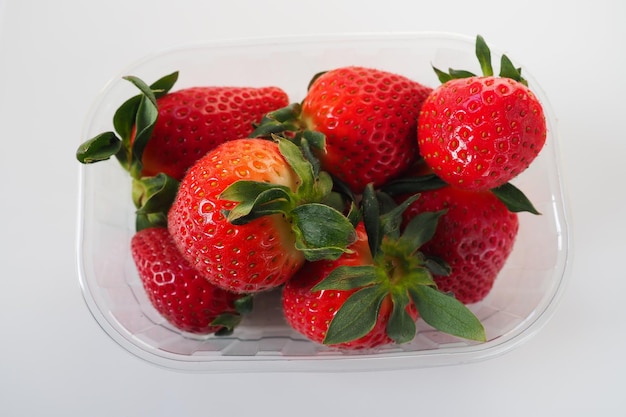 Fragole mature in una confezione di plastica su sfondo bianco deliziose bacche fresche in un contenitore per la vendita ai clienti mantenimento del cibo fresco vitamine e microelementi per alimenti sani