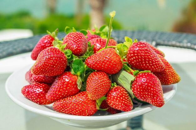 A ripe strawberries on a plate on a table.