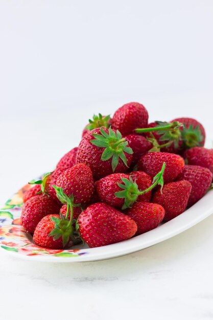 Ripe strawberries on a plate on a white background Summer berries