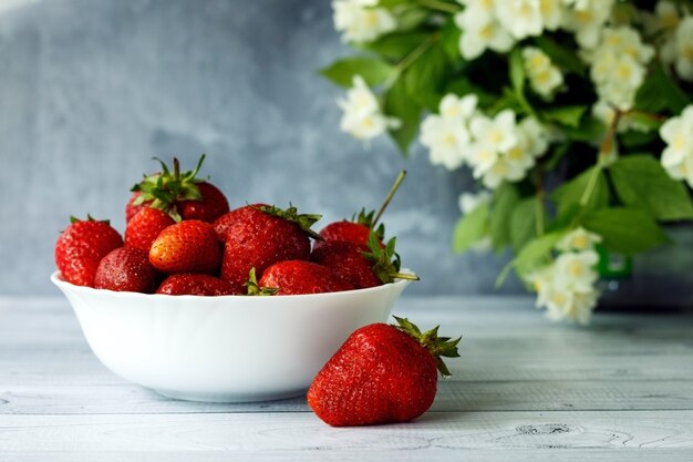 Ripe strawberries on a white plate and jasmine flowers