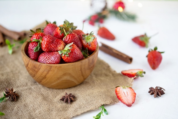 Ripe strawberries in a wooden bowl on a white table