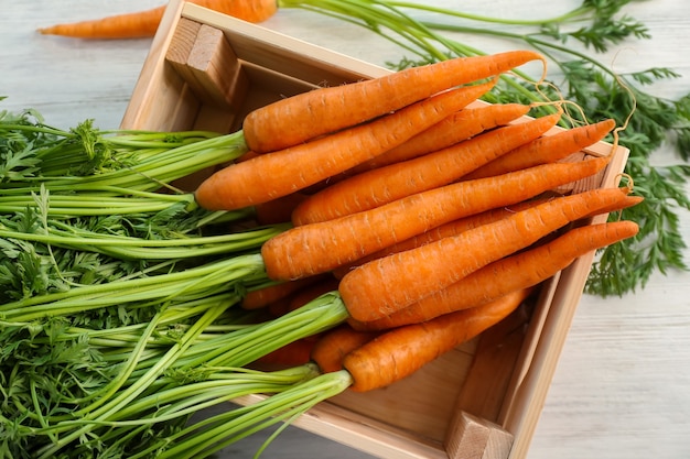 Ripe and sweet carrots in crate on wooden table