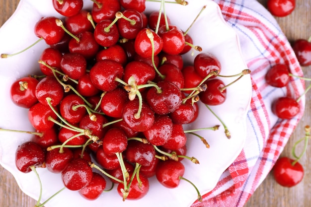 Ripe sweet cherries in bowl on wooden table