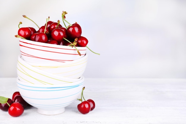 Ripe sweet cherries in bowl on wooden table