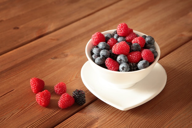 Ripe sweet different berries in white bowl on table Healthy organic food and nutrition concept