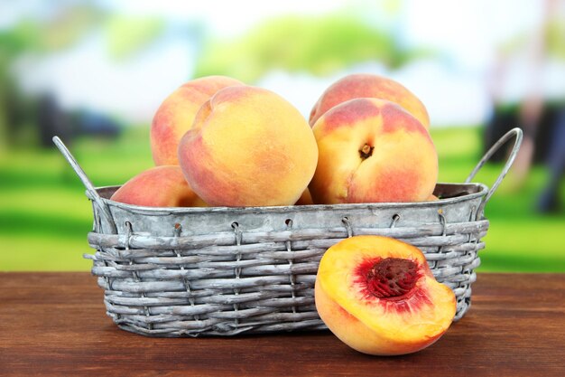 Ripe sweet peaches in wicker basket on bright background