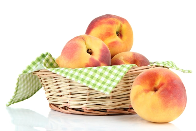 Ripe sweet peaches in wicker basket isolated on white