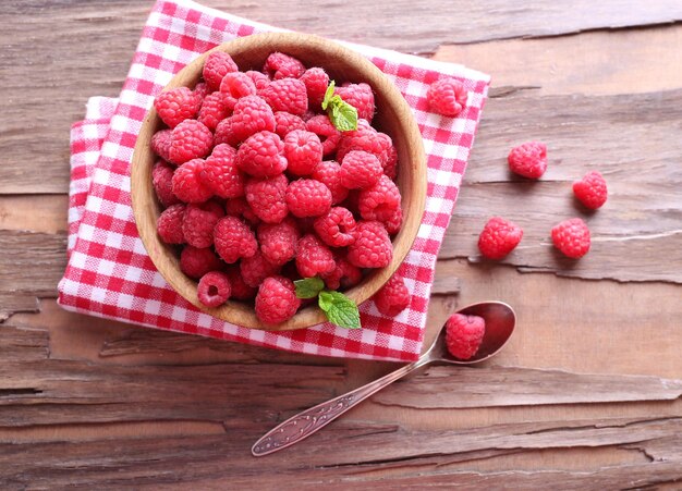 Ripe sweet raspberries in bowl on table closeup