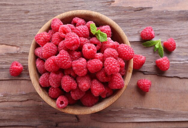 Ripe sweet raspberries in bowl on table closeup
