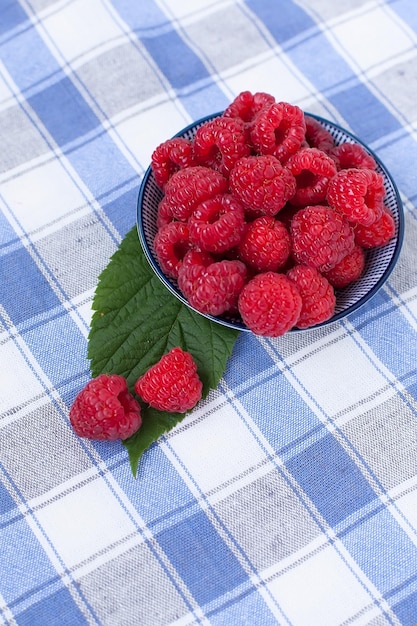 Ripe sweet raspberries in bowl on wooden table Close up top view high resolution product