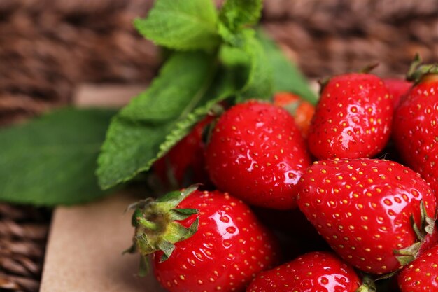 Ripe sweet strawberries on paper napkin on wicker mat background