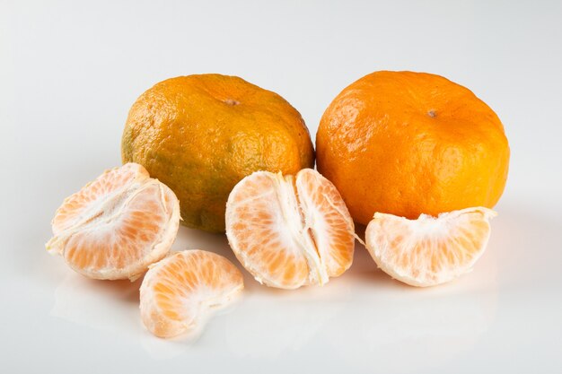 Ripe tangerine fruit with pieces on white background.