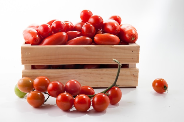 Ripe tomatoes on lie in a wooden box on a white background