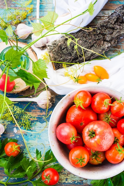 Ripe tomatoes in a plate on a wooden table. Top view