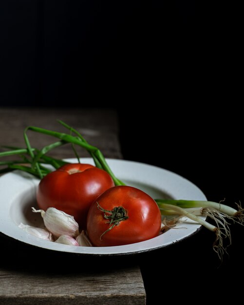 Ripe tomatoes and scallions on old wooden table.