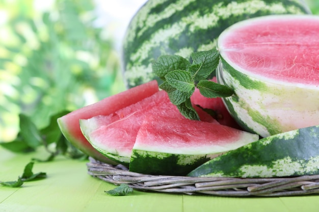 Ripe watermelons on wicker tray on wooden table on nature background