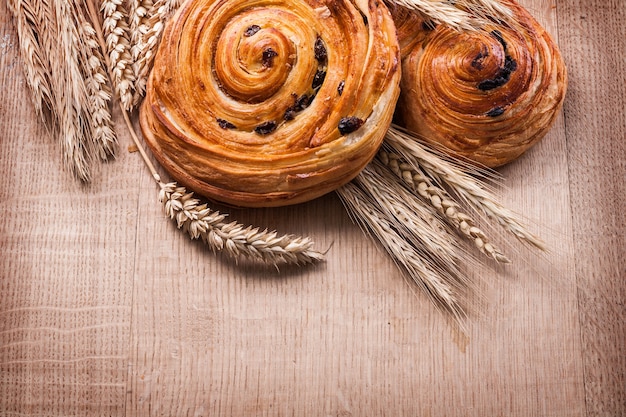 熟した小麦の穂レーズン焼きロールパンオークの木板の食べ物や飲み物のコンセプト
