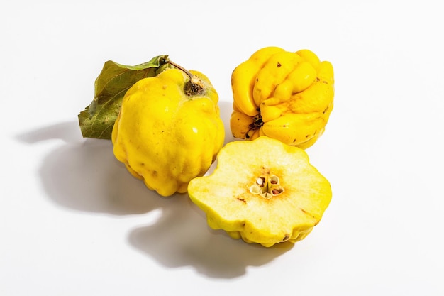 Ripe whole and cut quince isolated on white background. Fresh fruit, an essential ingredient for a healthy food. Trendy hard light, dark shadow