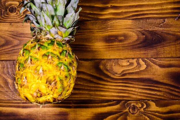 Ripe whole pineapple on rustic wooden table. Top view