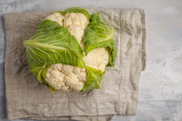 Ripe whole raw cauliflower on a light background on a napkin, top view. Healthy vegan food concept.