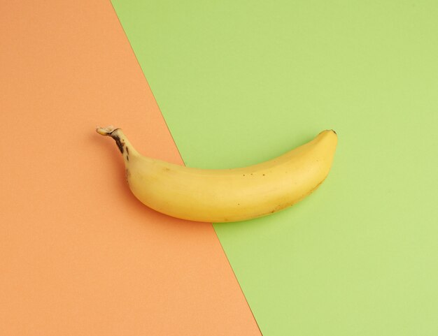 Ripe yellow banana on a colored background, top view