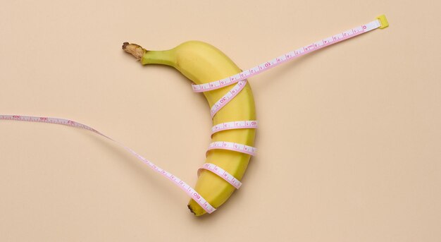 Ripe yellow banana wrapped in a measuring tape weight loss concept top view