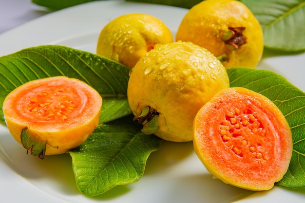 Frutti gialli maturi e foglie di guava su sfondo bianco
