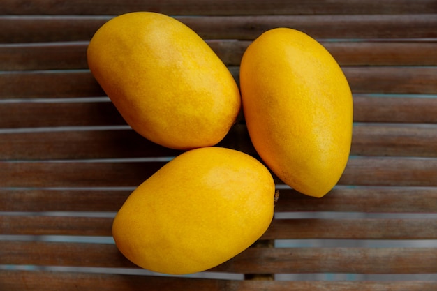 Ripe yellow mango on a wooden plank surface