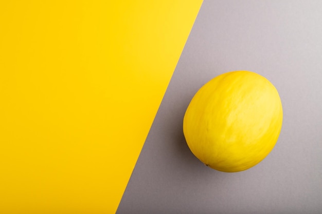 Ripe yellow melon on gray and yellow pastel background Top view copy space