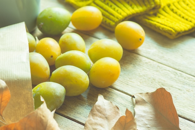 Photo ripe yellow transparent plums in brown craft paper bag scattered