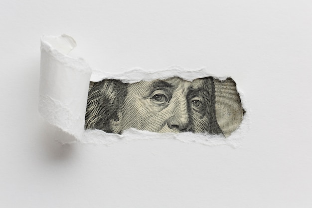 Photo ripped paper revealing dollar bill