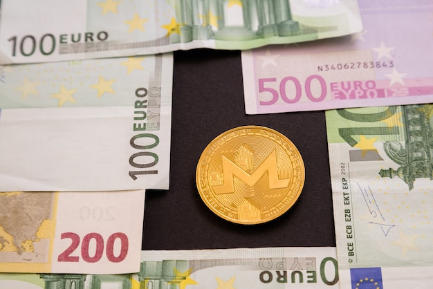 Монета ряби рядом с банкнотами евро на черной поверхности.