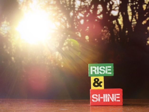 RISE AND SHINE written on wooden tiles with background of bokeh sunrise Copy space for text