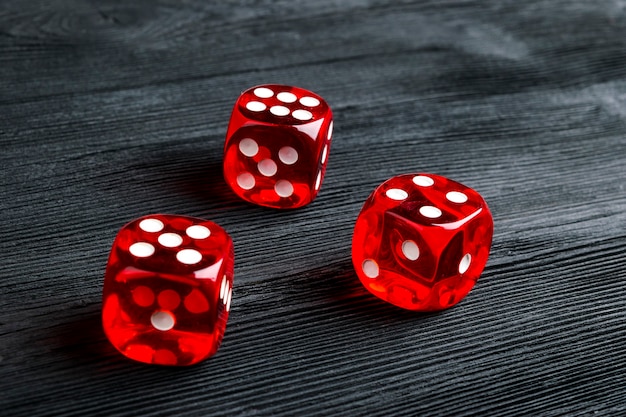 Foto risico concept - dobbelstenen spelen op zwarte houten achtergrond. een spel spelen met dobbelstenen. rode casino dobbelstenen rollen. rolling the dice concept voor bedrijfsrisico, kans, geluk of gokken