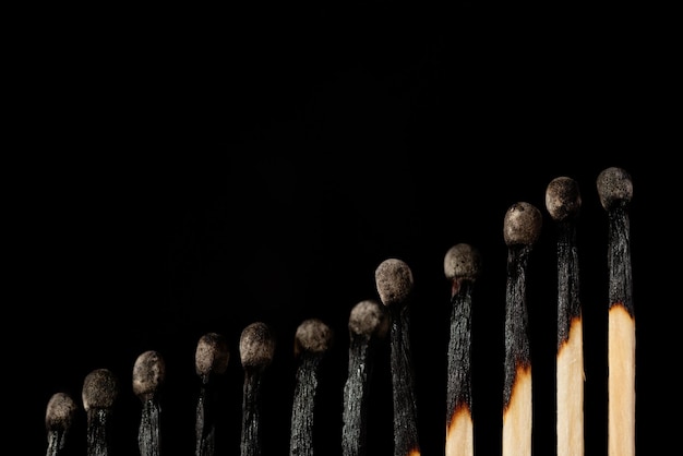 Photo rising line of burnt matches against black background. concept of uprise movement, positive statistics, elevation