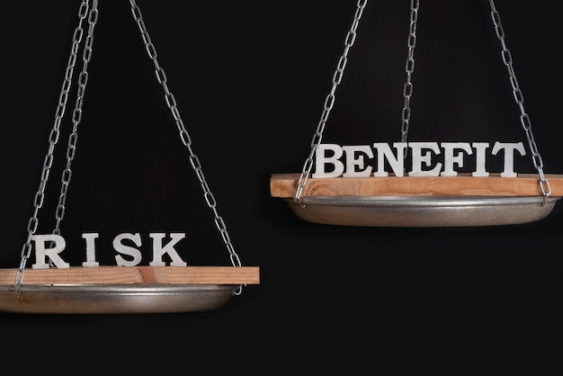 Photo risk and benefit reward concept scales on black background close up