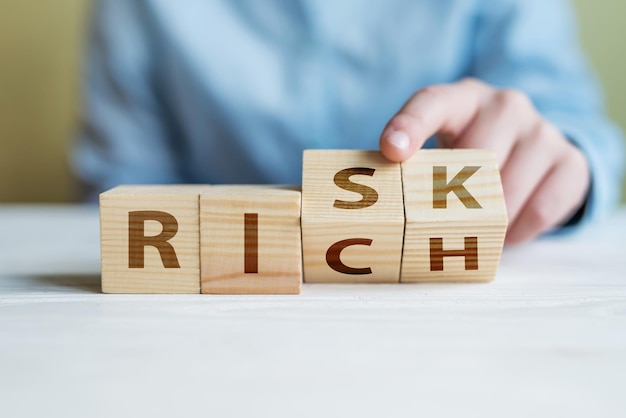 Risk or Rich concept Business womans hand changes the wooden cube